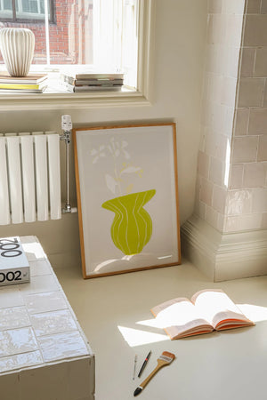 Plakat med grøn organisk form og fine linjer på lys baggrund i moderne indretning