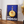 Vintage plakat med blå baggrund, en flaske Rossi aperitif og en glad appelsinfigur – retro reklameplakat med humor og farver.

