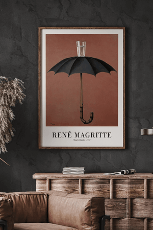 René Magritte plakat med sort paraply og glas vand ovenpå mod brun baggrund – surrealistisk kunstværk.

