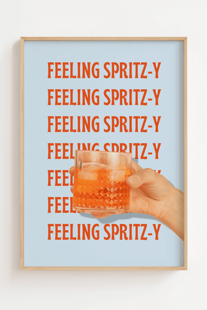 Plakat med teksten "Feeling Spritz-y" i rød-orange skrift gentaget på lyseblå baggrund, med en hånd der holder et glas Aperol Spritz.

