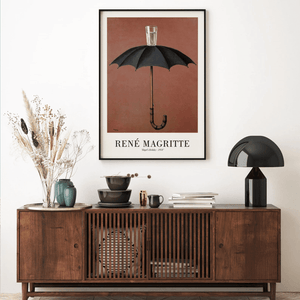 René Magritte plakat med sort paraply og glas vand ovenpå mod brun baggrund – surrealistisk kunstværk.