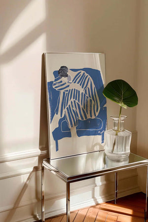 Kunstnerisk plakat med siddende figur i blå striber og bløde former på lys baggrund