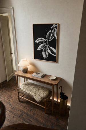 Botanisk gren plakat i sort ramme over kommode i stue