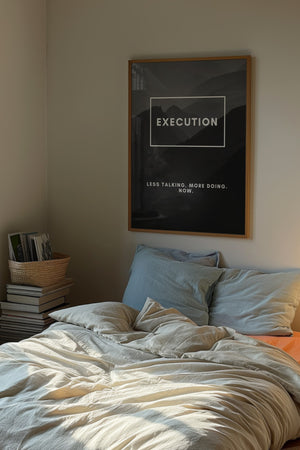 Execution plakat med hvid typografi i egetræsramme over seng