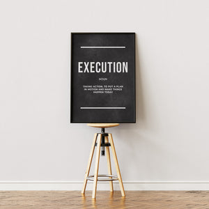 Execution Definition plakat med stor typografi på sort baggrund i egetræsramme på staffeli