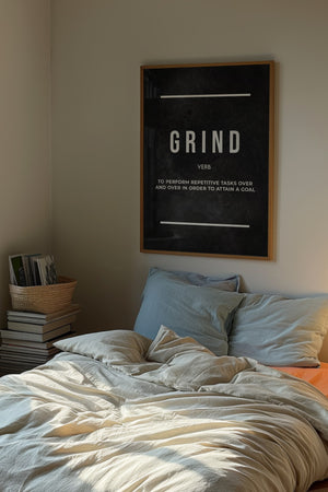 Grind Definition plakat med hvid typografi på mørk baggrund i egetræsramme over seng