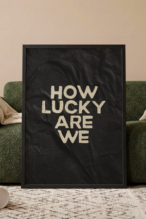 How Lucky Are We plakat i egetræsramme ved sofa