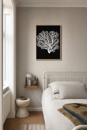 Hvid koral plakat i sort ramme over reol i moderne stue