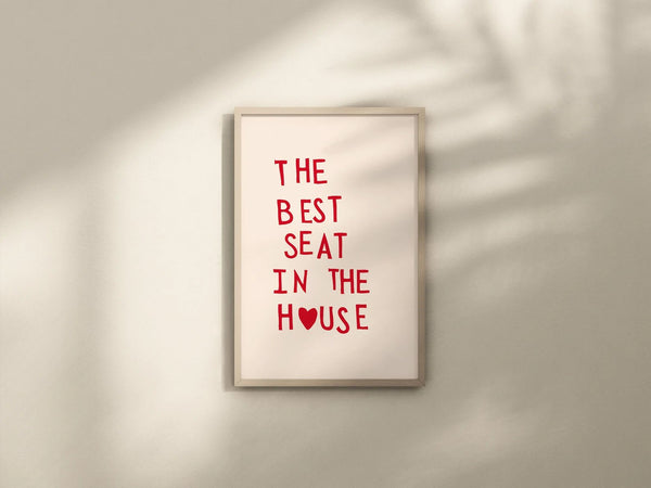 Plakat med rød tekst “The Best Seat in the House” og hjerte – humoristisk vægkunst til badeværelse eller gæstetoilet, indrammet og opstillet i moderne interiør.