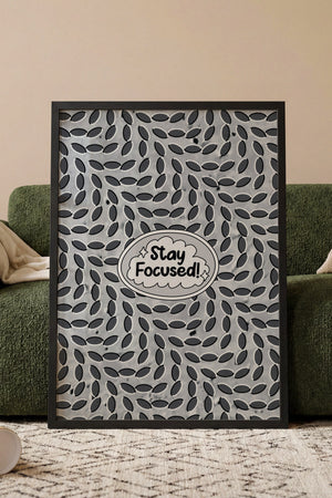 Stay Focused motivationsplakat med tekst i talesky og mønster af mørke ovaler i egetræsramme ved sofa